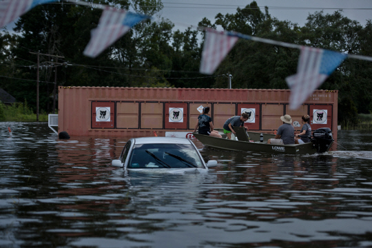 16일(현지시간) 폭우가 내린 루이지애나주 곤잘레스에서 자동차가 물에 둥둥 떠 있다. 차 옆으로는 사람들이 보트에 올라타 이동하고 있다. 이번 역사적인 폭우로 3만명이 넘는 이들이 구조됐다. /곤잘레스=AFP연합뉴스