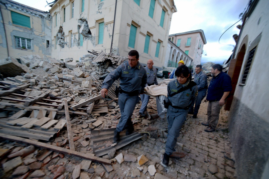 24일(현지시간) 새벽 규모 6.2의 강진이 발생한 이탈리아 중부 아마트리체에서 구조대원들이 붕괴된 건물 잔해 사이에서 부상자를 옮기고 있다. /아마트리체=AFP연합뉴스