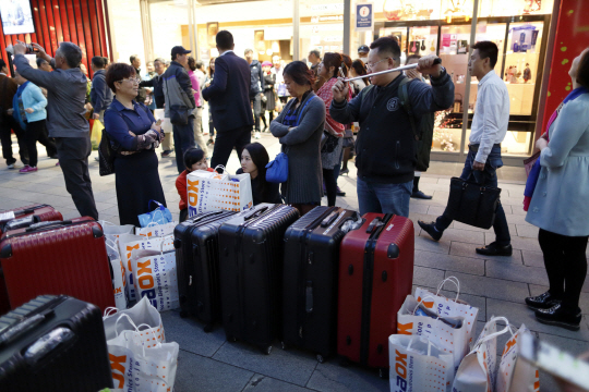 일본 도쿄 긴자에서 중국인 관광객들이 쇼핑한 물건과 짐을 거리에 놓고 서 있다./도쿄=블룸버그통신