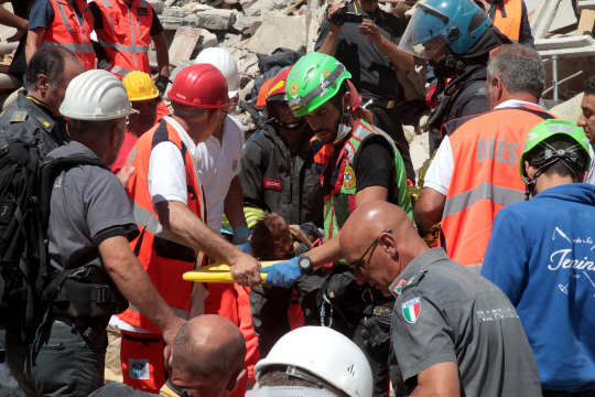25일(현지시간) 구급대원들이 지진 피해가 극심한 이탈리아 아마트리체 지역에서 어린이를 들 것에 실어 옮기도 있다. /아마트리체=UPI연합뉴스