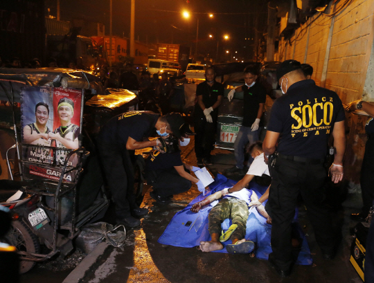 지난 20일(현지시간) 필리핀 경찰이 사살된 마약 용의자의 시신을 수습하고 있다. /연합뉴스