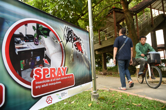 29일(현지시간) 최근 지카 바이러스 감염이 확인된 이들이 급증한 싱가포르에서 사람들이 모기 기피 스프레이 사용을 권하는 알림막 옆을 지나가고 있다. /싱가포르=AFP연합뉴스