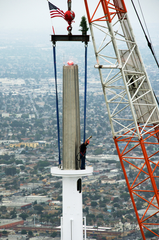 미국 로스앤젤레스(LA)에 있는 월셔 그랜드 타워의 첨탑 위로 3일(현지시간) 조형물이 설치되고 있다. 이날 첨탑 완공으로 이 건물의 높이는 1,099피트를 달성해 미 서부지역에서 최고층 건물이 됐다. /로스앤젤레스=AP연합뉴스