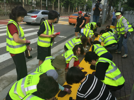 동부화재 설계사들이 지난 5일 서울 서초구 서초초등학교 인근 횡단보도에 옐로카펫을 설치하고 있다. 옐로카펫은 횡단보도 신호대기공간을 노란색으로 구획화한 것으로, 운전자들이 어린이 보행자를 쉽게 알아볼 수 있도록 도와준다. 이날 행사는 동부화재가 지난 7월 서울시와 어린이 보호구역 교통안전을 위해 ‘옐로카펫 100개소 설치 사업’ 지운 협약을 맺은 데 따른 것으로, 동부화재 강남사업단 소속 설계사 50여명은 서초초를 비롯해 서원초, 잠원초 앞에도 옐로카펫을 설치했다. /사진제공=옐로카펫