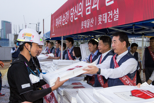 박현철(오른쪽) 롯데물산 사업총괄본부장이 롯데월드타워 현장 근로자들에게 명절 선물을 건네고 있다./사진제공=롯데물산