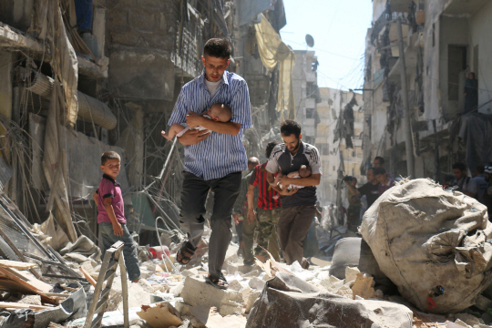 지난 11일 시리아 반군이 장악한 알레포 북부의 살리힌 지역에서 공습 소식이 전해지자 남성들이 아이들을 품에 안고 피신하고 있다./알레포=AFP연합뉴스