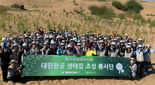 중국 네이멍구 쿠부치 사막에서 나무심기 봉사활동에 참가한 대한항공 직원들과 중국 대학생들이 기념 촬영을 하고 있다. /사진제공=대한항공