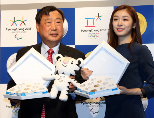 평창 올림픽 홍보대사 김연아(오른쪽)와 이희범 조직위원장이 22일 대회 기념주화를 들어 보이고 있다. /연합뉴스