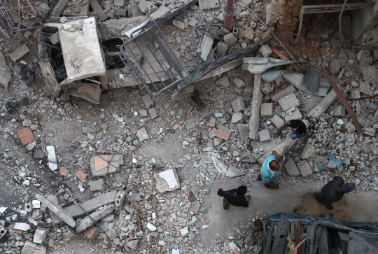 3일(현지시간) 시리아 알레포 지역에서 주민들이 공습으로 무너진 건물 잔해 옆을 걸어가고 있다. /알레포=AFP연합뉴스