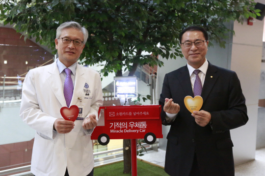 유구현(오른쪽) 우리카드 사장이 5일 세브란스 병원에서 ‘소원트리와 기적의 우체통’ 후원을 위한 지원금을 전달한 후 우체통에 소원카드를 넣고 있다./사진제공=우리카드
