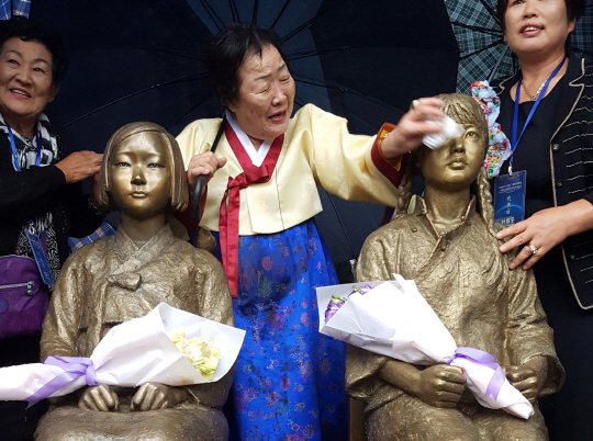 ‘일본군 성노예 피해 문제 유네스코 세계기록유산 등재를 위한 국제연대회의’가 22일 중국 상하이 사범대 앞 교정에 한중 위안부 ‘평화의 소녀상’을 제막한 가운데 행사에 참석한 이용수(가운데) 할머니가 소녀상의 얼굴을 닦아주고 있다. 중국에서 일본군 위안부 소녀상이 세워지기는 처음이다.  　 /연합뉴스