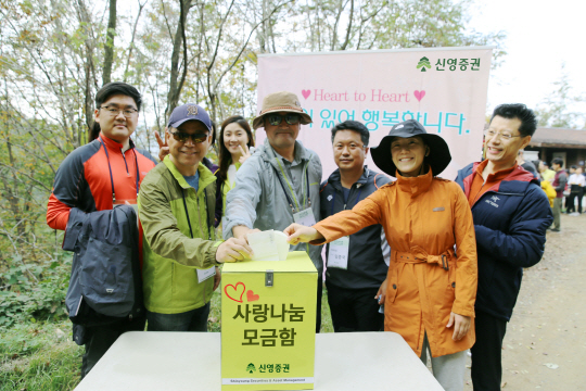 신요환(오른쪽에서 네번째) 신영증권 사장과 임직원들이 지난 23일 강원도 홍천에서 진행된 사랑나눔 트레킹 행사에서 모금함에 기부금을 보태고 있다. /사진제공=신영증권