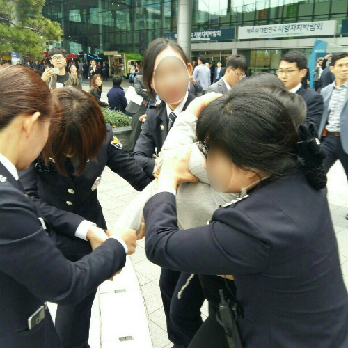 27일 박근혜 대통령이 참석한 부산 해운대구 벡스코 앞에서 박 대통령 하야 등을 요구하는 기습시위를 하던 대학생이 경찰에 연행되고 있다. /연합뉴스