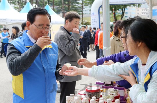 27일 서울 중구 신한은행 본점에서 열린 ‘결연마을과 함께하는 신한 따뜻한 장터’에서 한동우(왼쪽 첫번째) 신한금융그룹 회장이 농산품 판매장을 돌아보며 지역 특산품을 시음하고 있다. /사진제공=신한금융그룹