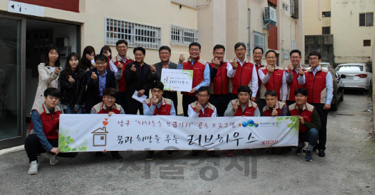 롯데건설 임직원들이 부산 남구 문현동과 용호동 지역에서의 주거환경 개선 봉사활동 기념 촬영을 하고 있다./롯데건설.