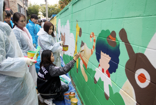 지난 10월31일 롯데자산개발 직원들이 서울 은평구 갈현초등학교 부근 담벼락에 벽화를 그리고 있다. /사진제공=롯데자산개발