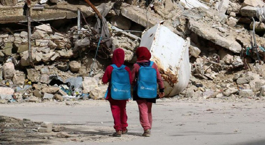 시리아 내전이 벌어지는 알레포를 걷는 두 소녀. 배낭은 유니세프에서 제공한 것이다.