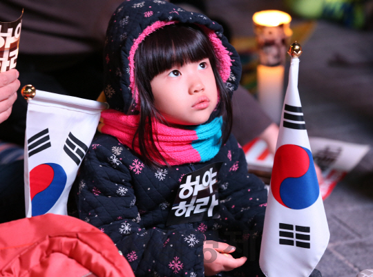 12일 오후 서울 광화문광장에서 열린 '내려와라 박근혜 3차 범국민행동'에 부모와 함께 참가한 어린이가 태극기를 흔들고 있다./권욱기자ukkwon@sedaily.com