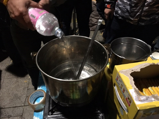 경복궁 사거리에 한 시민이 곳곳에서 추위에 떨 시민들을 위해 커피와 코코아를 준비하고 있다. 물을 끓이기 위해 빈 냄비에 생수를 붓고 있다. /정수현기자