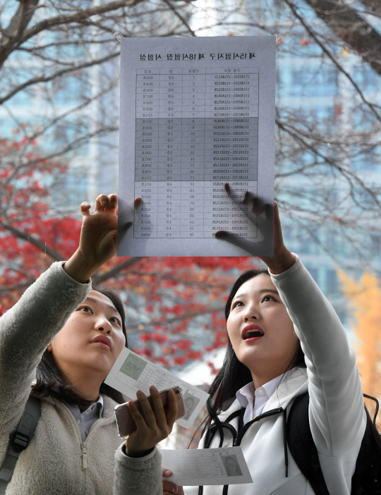 대학수학능력시험을 하루 앞둔 16일 서울 중구 이화여고에서 수험생들이 수험표를 받은 후 시험장을 확인하고 있다. /권욱기자