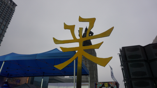 노란색으로 ‘꽃’이란 문구를 만든 조형물. 광화문 광장에 세워진 세워호 부스 옆에 어우러져 서있다.