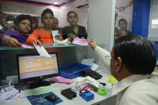 지난 25일(현지시간) 인도 서북부 암리차르의 한 은행에서 직원이 유통이 금지된 고액 화폐의 교환을 요청하는 손님들에게 돈을 내어주고 있다. /암리차르=AFP연합뉴스