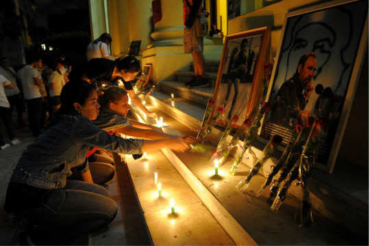 26일(현지시간) 쿠바 수도 아바나에서 피델 카스트로 전 국가평의회 의장의 죽음을 애도하는 학생들이 그의 사진 아래 촛불을 켜고 꽃을 놓고 있다./AFP연합뉴스