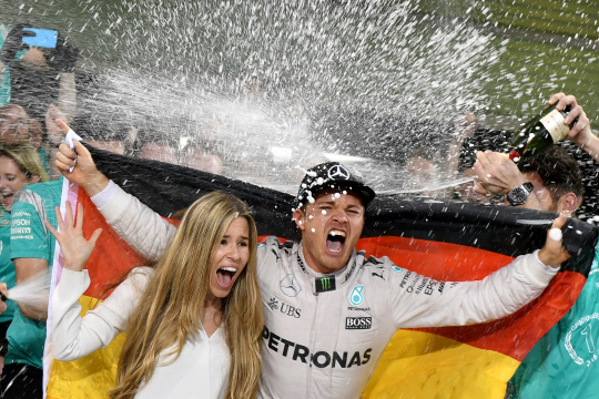니코 로스베르크(오른쪽)와 그의 아내가 28일 F1 시즌 챔피언 등극을 확정한 뒤 팀원들의 샴페인 세례를 받고 있다. /아부다비=AFP연합뉴스