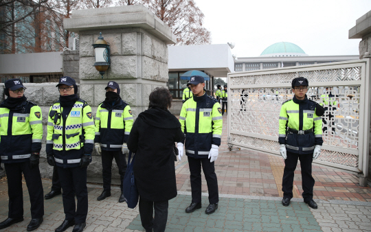 박근혜 대통령 탄핵소추안 표결을 하루 앞둔 8일 오후 국회 앞에서 경찰이 출입자의 신원을 확인하고 있다./연합뉴스