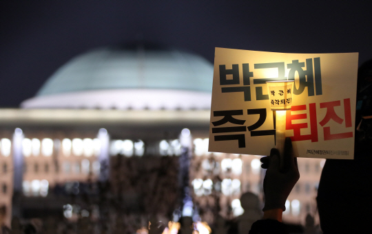 7일 저녁 국회 앞에서 열린 ‘국민과 함께하는 촛불 문화제’에서 참가자들이 박근혜 대통령의 탄핵을 촉구하는 촛불을 들고 있다. /연합뉴스