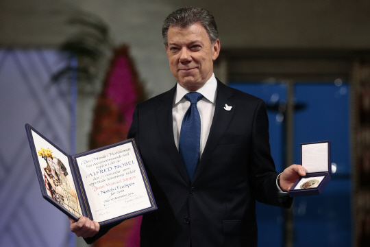 후안 마누엘 산토스 콜롬비아 대통령이 10일(현지시간) 노르웨이 오슬로 시청에서 2016년 노벨평화상을 수상한 후 메달과 증서를 내보이며 기념촬영을 하고 있다. /오슬로=AP연합뉴스