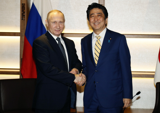 블라디미르 푸틴(왼쪽) 러시아 대통령과 아베 신조 일본 총리가 15일 일본 야마구치현 나가토의 한 온천여관에서 정상회의를 시작하기에 앞서 악수를 하고 있다. /나가토=AP연합뉴스