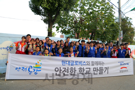 현대글로비스 직원과 가족들이 지난 10월 경기도 평택 오성중학교에서 학생들과 함께 학교 담장 총 50m에 걸쳐 안전과 관련된 벽화를 그리는 ‘안전공감 벽화 그리기’ 활동을 한 후 기념 촬영을 하고 있다. /사진제공=현대글로비스