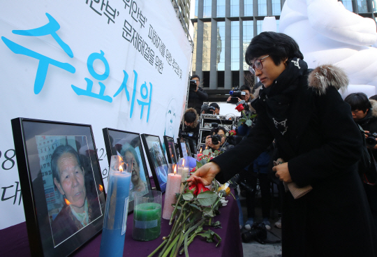 28일 서울 종로구 중학동 일본대사관 앞에서 열린 수요시위에서 참가자들이 올해 사망한 위안부 피해 할머니들의 영정 앞에 헌화하고 있다. 　   /연합뉴스