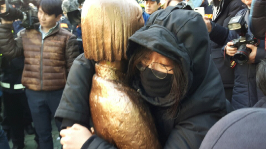 28일 부산 동구 일본영사관 인근 인도에서 ‘평화의 소녀상’을 설치한 한 학생이 소녀상을 붙잡고 철거를 막고 있다./사진제공=부산경찰청