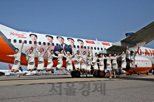 제주항공 승무원들이 광고모델 사진이 래핑된 자사 항공기 앞에서 힘차게 점프하고 있다. /사진제공=제주항공