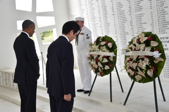 아베 신조(오른쪽) 일본 총리와 버락 오바마 미국 대통령이 27일(현지시간) 미국 하와이의 진주만 공습 희생자 추도시설인 애리조나기념관에서 헌화 후 묵념하고 있다. 아베 총리는 이날 연설에서 국제 평화와 미일 동맹의 중요성을 강조했지만 반성과 사과의 표현은 없었다. 외신들은 아베 총리가 미국과 달리 아시아 국가를 침략한 데 대해서는 침묵으로 일관하고 있다며 강력 비판했다.  /진주만=AFP연합뉴스