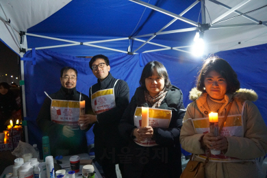 ‘인도주의실천의사협의회’ 소속 회원들이 31일 서울 종로구 광화문 광장에 설치된 임시 진료소에서 촛불을 들어 보이고 있다./이종호 기자