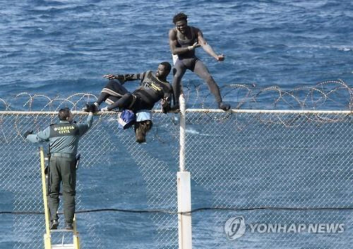 스페인·모로코 국경의 철조망을 넘으려는 불법 이민들/EPA=연합뉴스