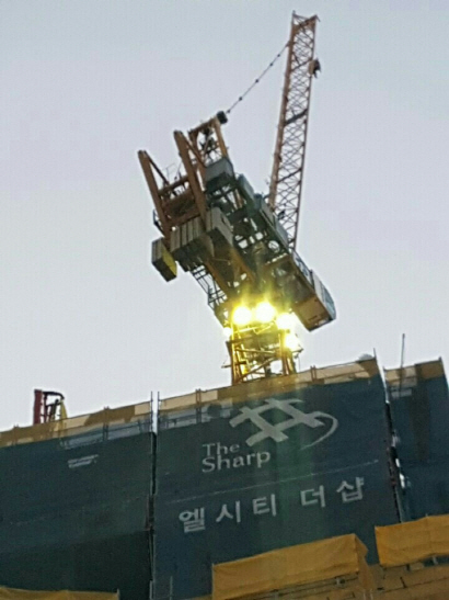 해운대 엘시티(LCT) 건설현장 식당 업주로 보이는 한 여성이 크레인에 올라가 “밀린 식비를 달라”며 농성을 벌이고 있다./사진제공=부산경찰청