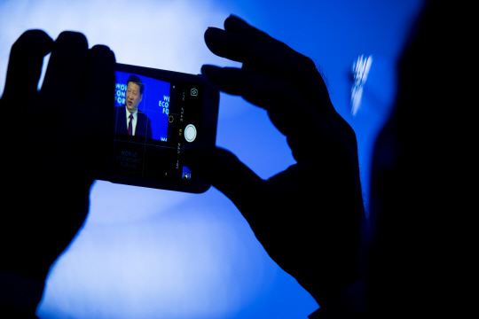 17일(현지시간) 스위스의 세계경제포럼(WEF)에 참석한 한 사람이 개막연설을 하고 있는 시진핑 중국 국가주석을 스마트폰으로 촬영하고 있다./AP연합뉴스