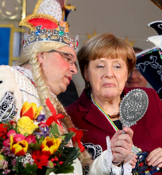 앙겔라 메르켈(오른쪽) 독일 총리가 23일(현지시간) 베를린 총리관저에서 열린 카니발협의회 초청 행사에서 한 단원이 들어올린 거울을 보며 익살스러운 표정을 짓고 있다. 이번 행사는 다음달 독일에서 전국적으로 열리는 카니발 기간을 앞두고 개최됐다.   /베를린=AFP연합뉴스