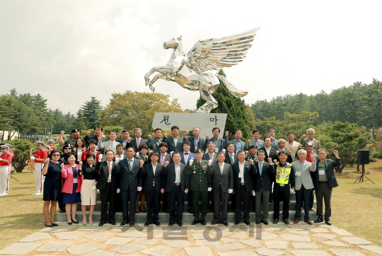 육군 7공수특전여단 상징탑인 ‘천마상’ 앞에서 강용면 작가(뒷 줄 오른쪽 끝)와 장병 및 예비역, 지역기관장들이 함께 기념촬영하고 있다