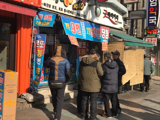 지난 1일 낮 서울 종로구의 한 복권방 앞에서 시민들이 구매한 로또의 번호를 확인하고 있다.  　  /이두형기자