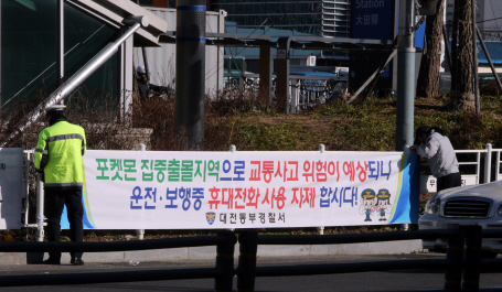 대전 동부경찰서 관계자들이 지난 1일 대전역 앞에 ‘포켓몬 집중 출몰 지역으로 교통사고 위험이 예상되니 운전·보행중 휴대전화 사용 자제합시다’라는 현수막을 걸고 있다. /대전=연합뉴스
