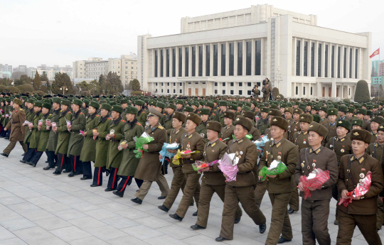 북한 인민군 장병들과 근로자, 학생들이 지난 8일 정규군 창설 69돌을 맞아 꽃바구니를 김정일 국방위원장의 동상에 올리고 있다. /연합뉴스