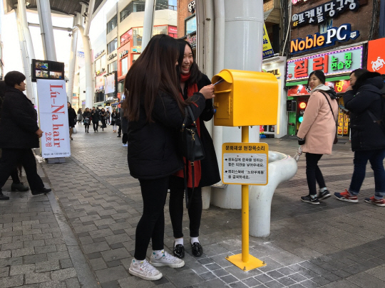 젊은 여성들이 대전시 중구 은행동 으능정이 거리에 설치된 노란우체통에 문화재생 정책과 관련한 의견을 담은 편지를 넣고 있다. /사진제공=대전시