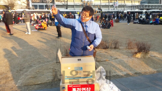 18일 서울 광화문 광장 일대에서 열린 16차 촛불집회에 참가한 한 시민이 태극기 문양이  새겨진 의료용 밴드를 시민들에게 나눠주고 있다./박우인 기자