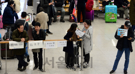 중국 정부의 한국여행상품 판매 중단 지시가 내려진 가운데 3일 오전 인천국제공항 입국장에서 중국어 팻말을 든 관광가이드들이 심각한 표정으로 이야기를 나누고 있다./영종도=이호재기자.