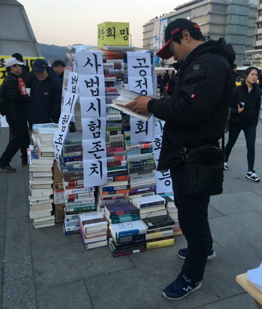 4일 광화문 광장에서 ‘사법시험 존치를 위한 서명 운동’의 참가자가 사시 수험서를 보고 있다./변수연기자